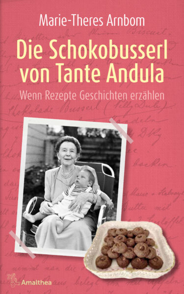 Das Buchcover von Marie-Theres Arnbom "Die Schokobusserl von Tante Andula" zeigt eine Fotografie von Tante Andula mit einem Baby im Arm. Das Bild ist auf einem rosaroten Hintergrund durch Klebestreifen befestigt. Darüber befindet sich, leicht versetzt, ein Bild von Schokobusserl. Darüber ist der Titel "Die Schokobusserl von Tante Andula" und der Name der Autorin "Marie-Theres Arnbom" zu sehen. Im rosaroten Hintergrund ist blass handschriftlich ein Rezept geschrieben.